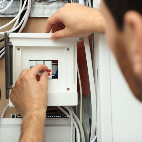 Electrician switching off circuit breakers in fuse box, closeup